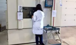 Opératrice d'essais devant son enceinte d'essais chocs thermiques