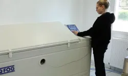 Opératrice devant une enceinte de brouillard salin